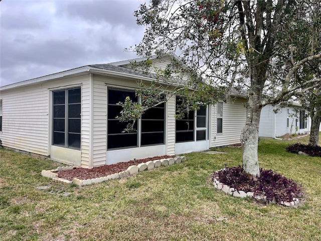 view of property exterior with a sunroom and a lawn