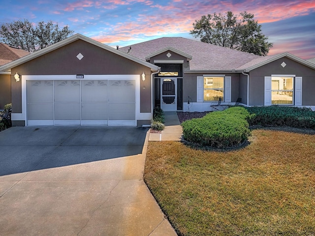 ranch-style home featuring a garage and a yard