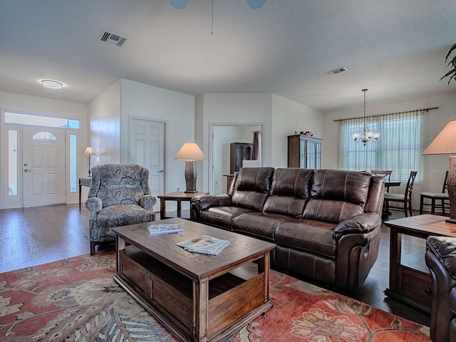 living room with hardwood / wood-style floors, a notable chandelier, and a textured ceiling