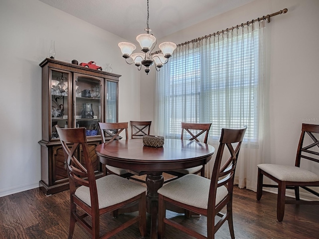 dining space with plenty of natural light, dark hardwood / wood-style floors, and an inviting chandelier