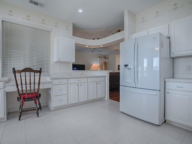 kitchen featuring light tile patterned floors, built in desk, white refrigerator with ice dispenser, and white cabinets