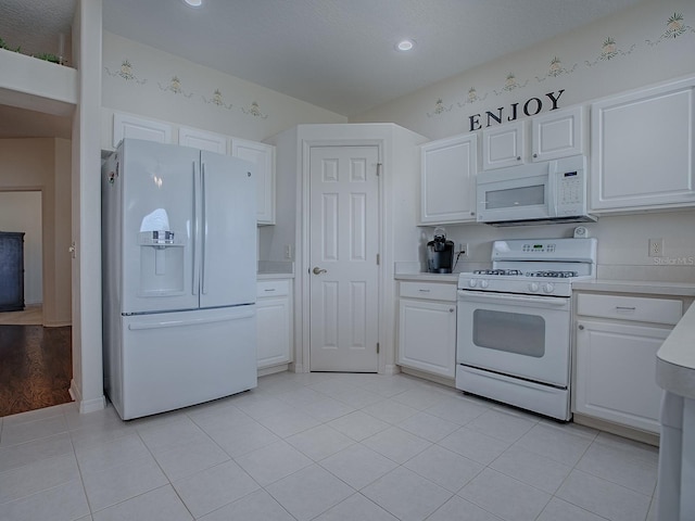 kitchen featuring light tile patterned floors, white cabinets, and white appliances