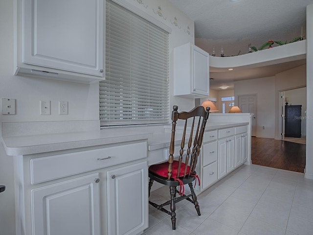 kitchen featuring built in desk, kitchen peninsula, white cabinets, and light tile patterned flooring