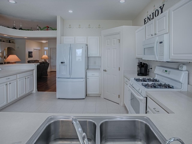 kitchen with white cabinetry, sink, light tile patterned flooring, and white appliances