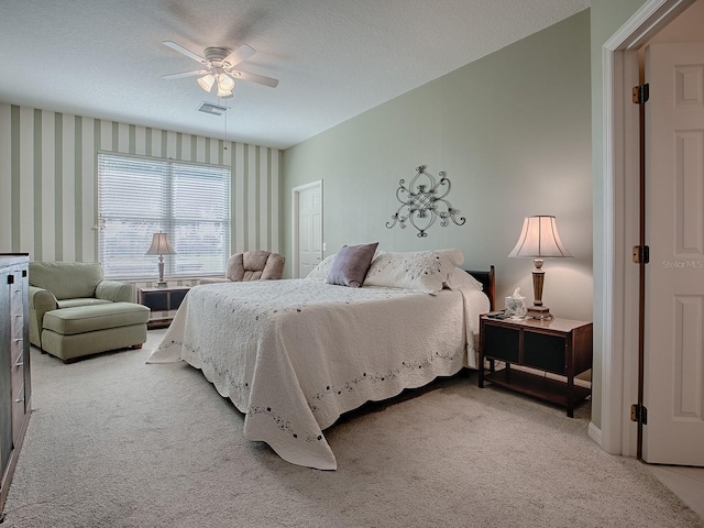 carpeted bedroom with ceiling fan and a textured ceiling