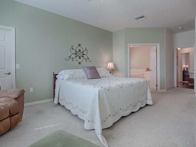 bedroom with ensuite bath and light carpet