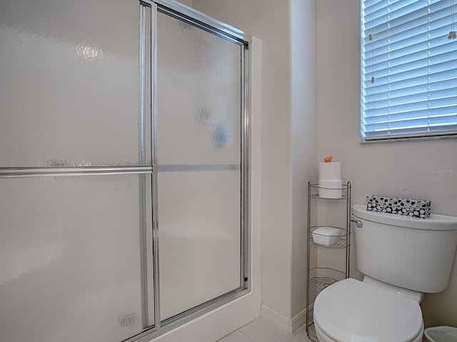 bathroom featuring toilet, tile patterned floors, and a shower with shower door