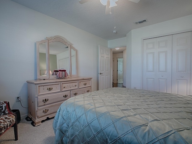 carpeted bedroom featuring ceiling fan, a closet, and a textured ceiling