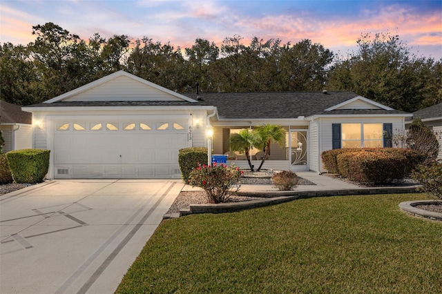 ranch-style house with a garage and a lawn