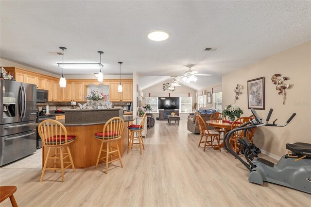 8373 SE 177th Bartram Loop, The Villages, FL 32162 - kitchen with hanging light fixtures, appliances with stainless steel finishes, light wood-type flooring, and a kitchen breakfast bar