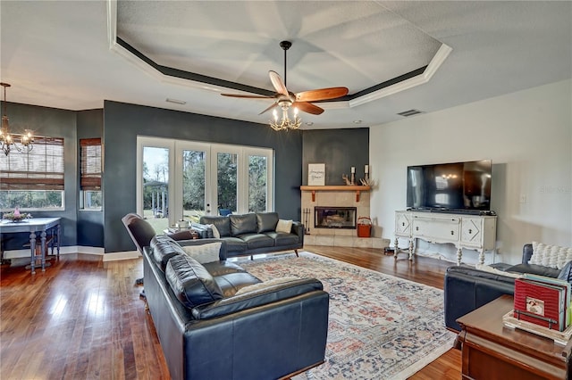 living room with dark wood-type flooring, a fireplace, and a tray ceiling