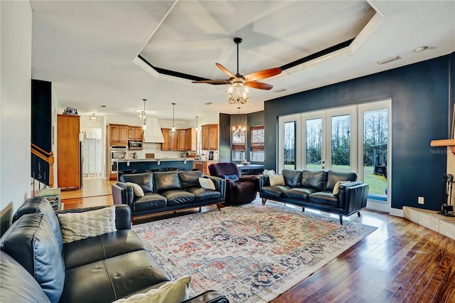 living room featuring ceiling fan, dark hardwood / wood-style flooring, and a raised ceiling