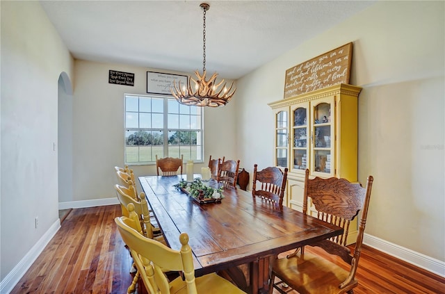 dining space featuring wood-type flooring and a chandelier