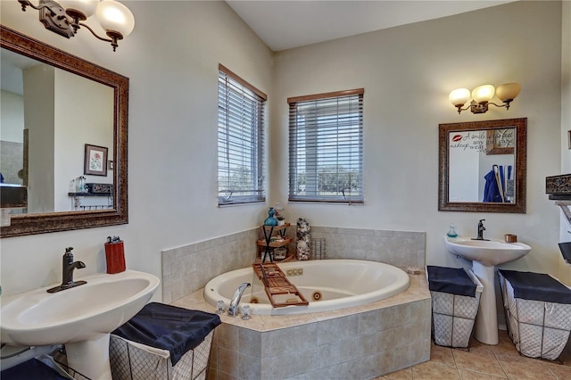 bathroom with dual sinks, tile patterned floors, and tiled bath