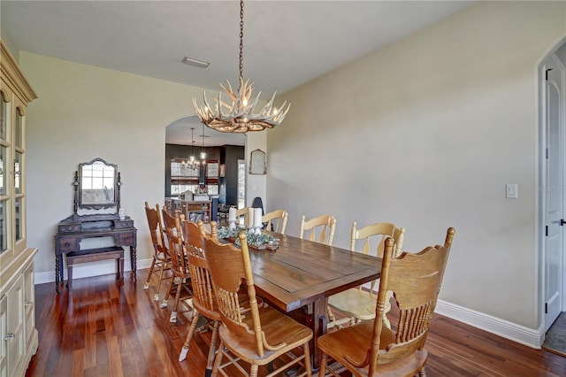 dining area featuring an inviting chandelier and dark wood-type flooring