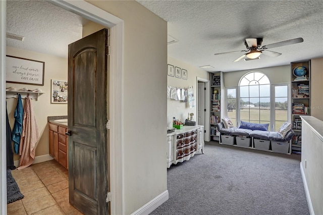 hall with light colored carpet and a textured ceiling