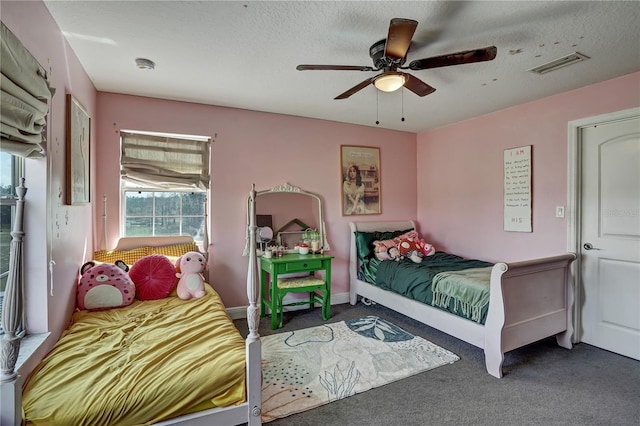 bedroom with a textured ceiling, ceiling fan, and dark colored carpet