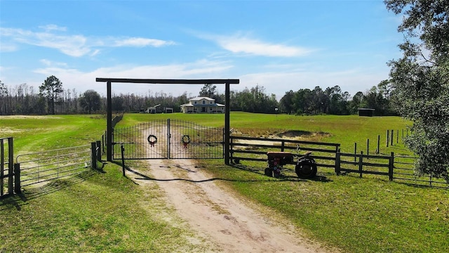 view of gate with a yard and a rural view