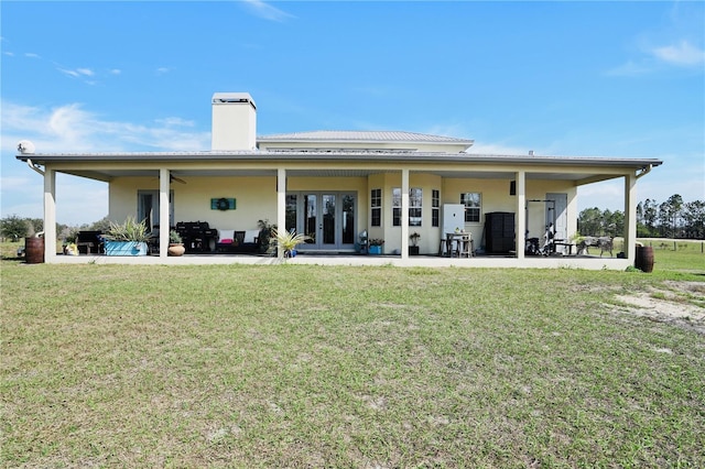 rear view of house featuring french doors, ceiling fan, a patio, and a lawn