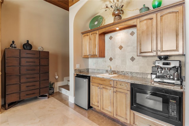 kitchen with sink, backsplash, fridge, black microwave, and light stone counters