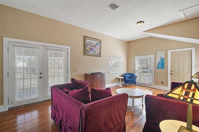 living room with lofted ceiling, hardwood / wood-style flooring, french doors, and a textured ceiling