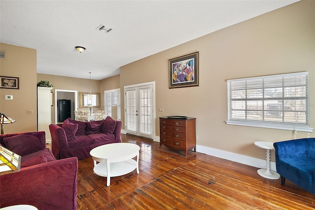 living room with french doors, plenty of natural light, hardwood / wood-style floors, and a textured ceiling