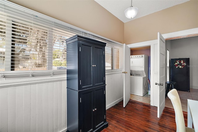 kitchen with pendant lighting, stacked washer / dryer, dark hardwood / wood-style flooring, and vaulted ceiling