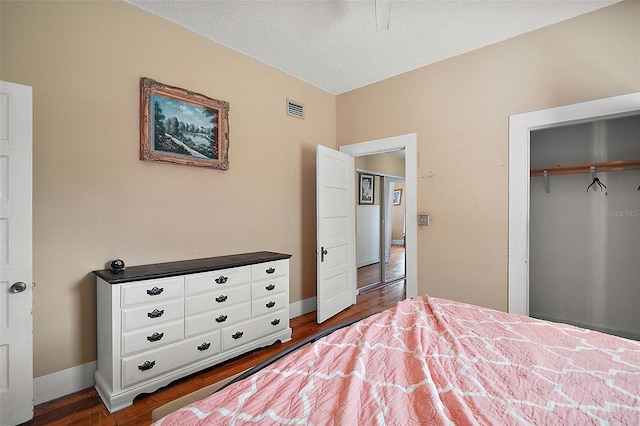 unfurnished bedroom featuring a textured ceiling, dark hardwood / wood-style flooring, and a closet