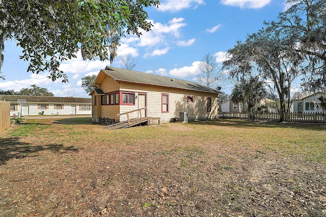 rear view of property featuring cooling unit and a lawn