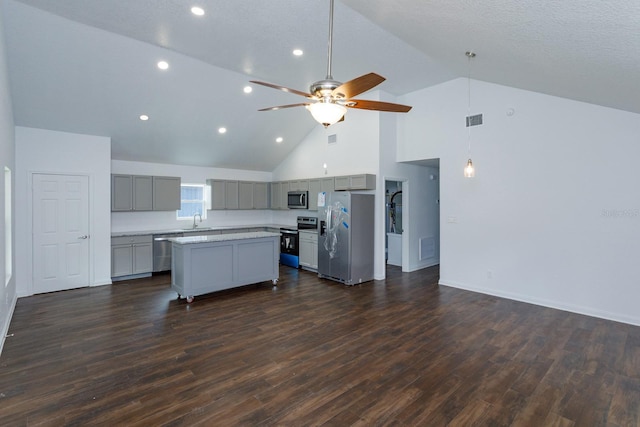 kitchen featuring appliances with stainless steel finishes, sink, gray cabinetry, a center island, and dark wood-type flooring