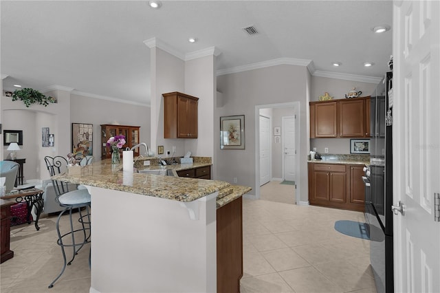 kitchen with lofted ceiling, light stone countertops, sink, light tile patterned floors, and a kitchen bar