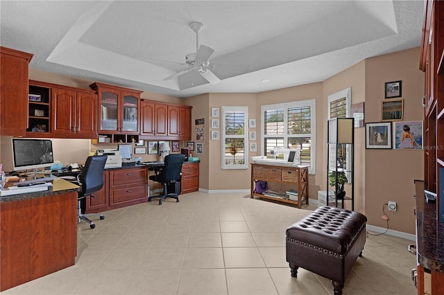 tiled office space featuring ceiling fan, a tray ceiling, a textured ceiling, and built in desk