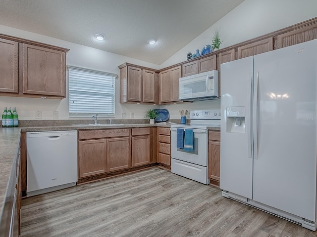 kitchen with lofted ceiling, sink, white appliances, light hardwood / wood-style floors, and a textured ceiling