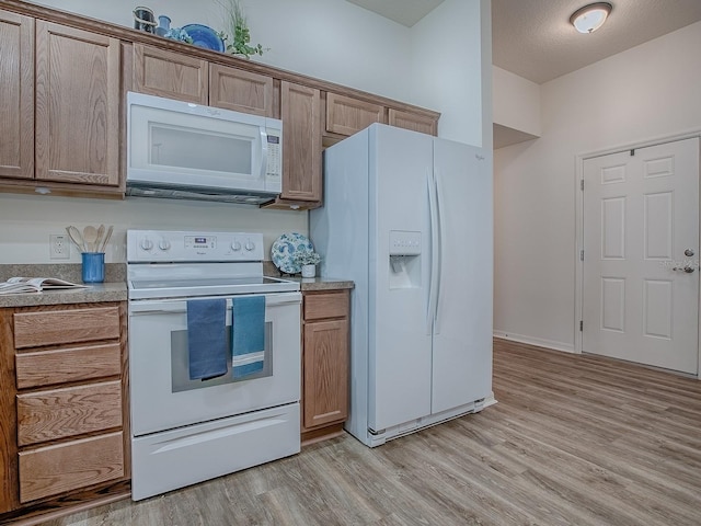 kitchen featuring white appliances, a textured ceiling, and light wood-type flooring
