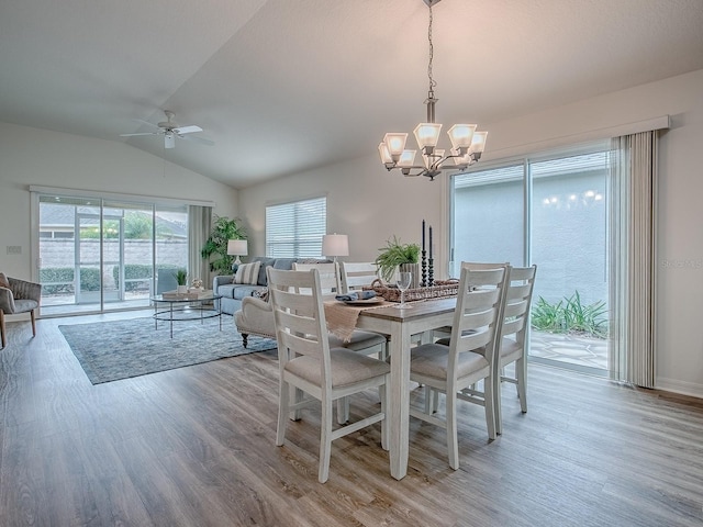 dining area featuring vaulted ceiling, ceiling fan with notable chandelier, and light hardwood / wood-style floors
