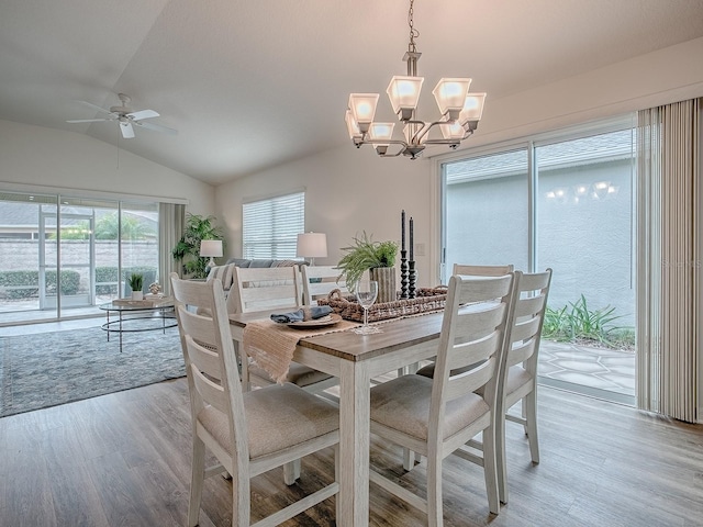 dining space with ceiling fan with notable chandelier, lofted ceiling, and light hardwood / wood-style floors