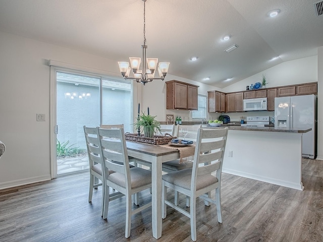 dining room with lofted ceiling, an inviting chandelier, a textured ceiling, and light wood-type flooring