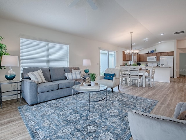 living room with light hardwood / wood-style floors, vaulted ceiling, and a wealth of natural light