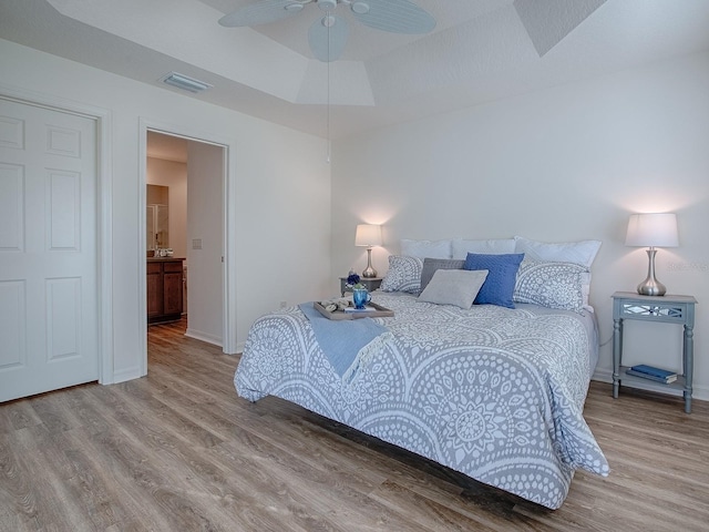 bedroom featuring a raised ceiling and light hardwood / wood-style flooring