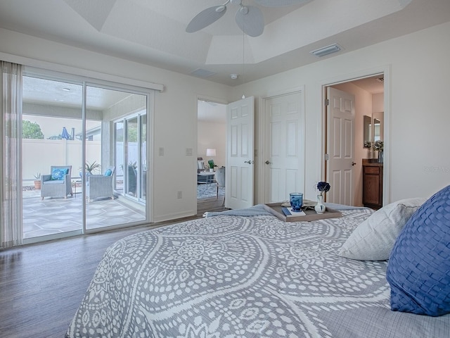 bedroom featuring wood-type flooring, a tray ceiling, and access to outside