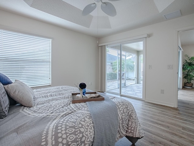 bedroom featuring ceiling fan, access to exterior, hardwood / wood-style floors, and a textured ceiling