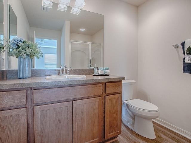 bathroom with hardwood / wood-style flooring, vanity, toilet, and a shower with shower door