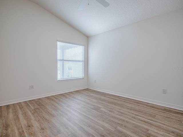 empty room featuring lofted ceiling, ceiling fan, light hardwood / wood-style floors, and a textured ceiling
