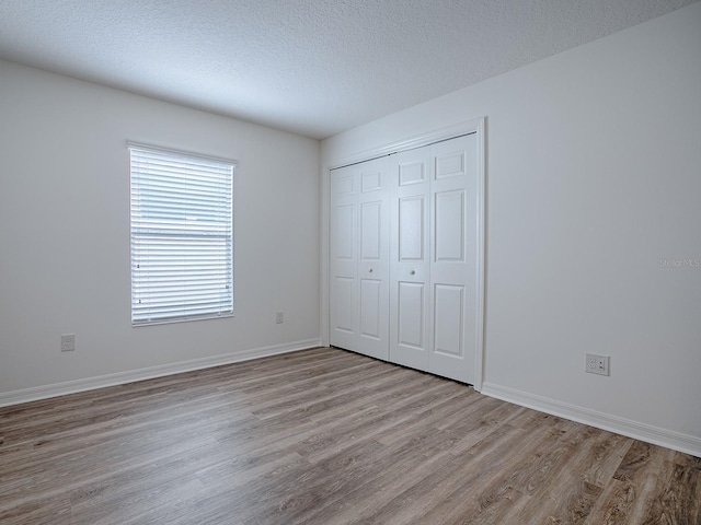 unfurnished bedroom with light hardwood / wood-style flooring, a closet, and a textured ceiling