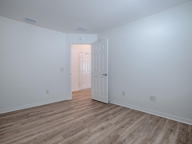 empty room featuring light hardwood / wood-style flooring and a textured ceiling
