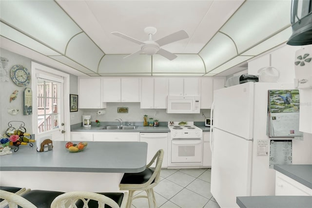 kitchen with white appliances, light tile patterned flooring, sink, white cabinetry, and a kitchen bar