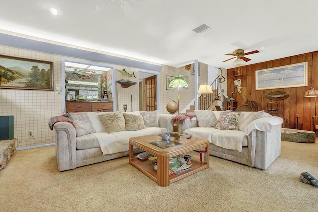 carpeted living room with a tiled fireplace and ceiling fan