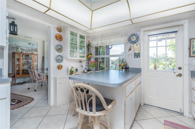 kitchen featuring white cabinets, light tile patterned floors, and kitchen peninsula