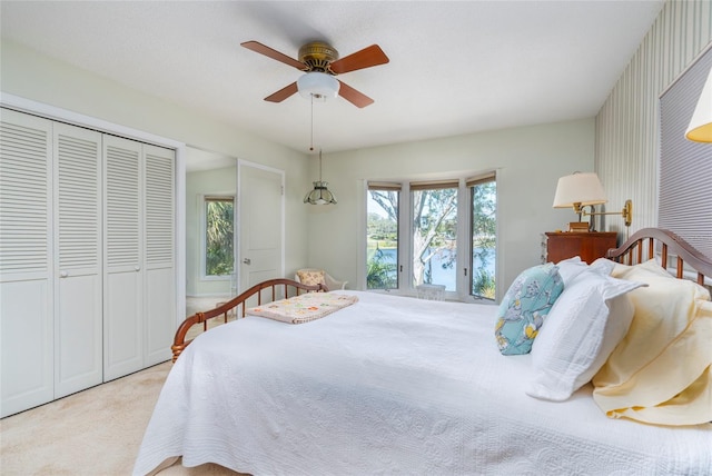 bedroom with multiple windows, light carpet, ceiling fan, and a closet