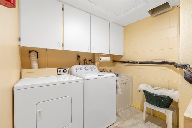 washroom with cabinets, washing machine and dryer, and light tile patterned floors